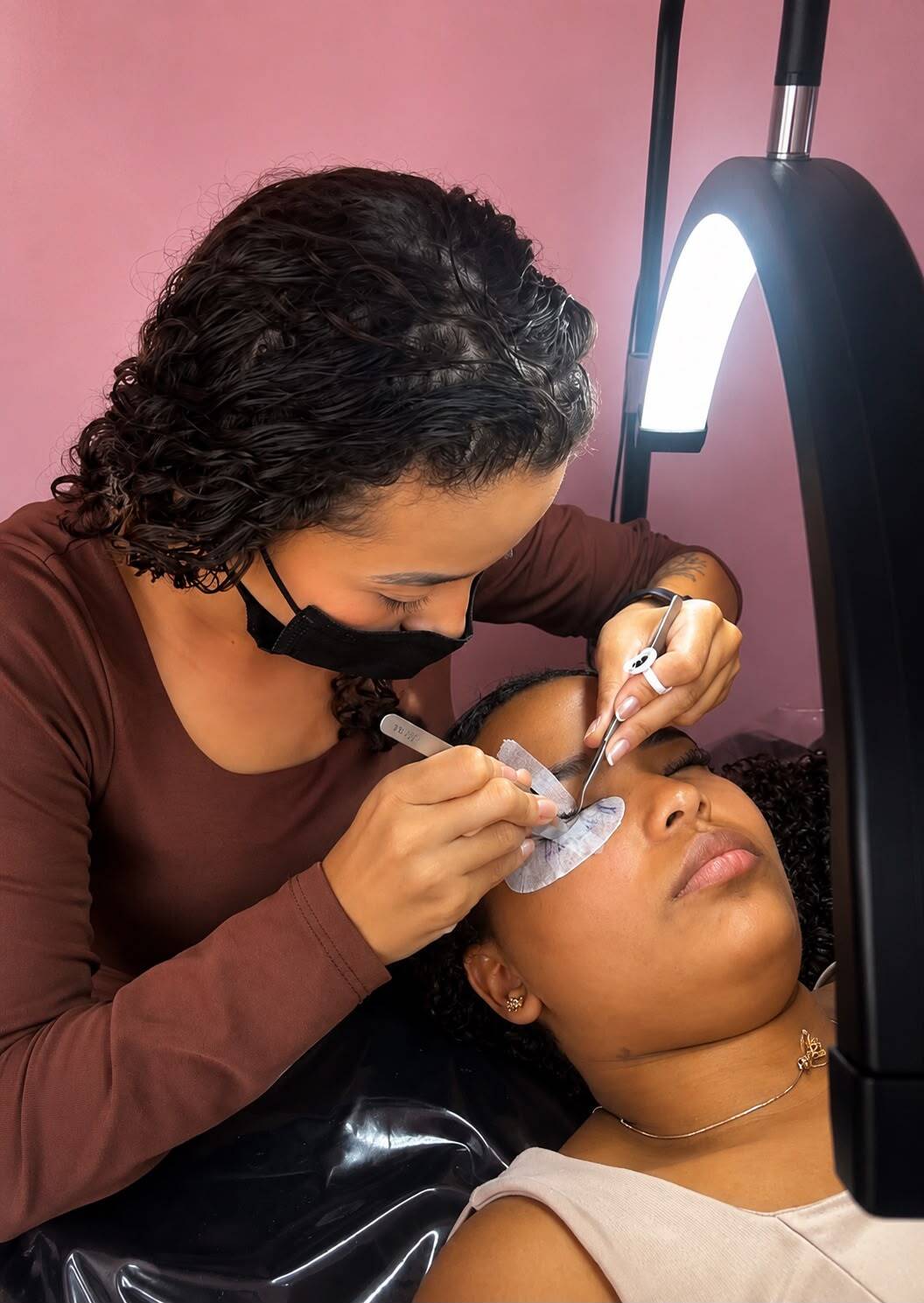 Aluna praticando extensão de cílios em uma modelo real
